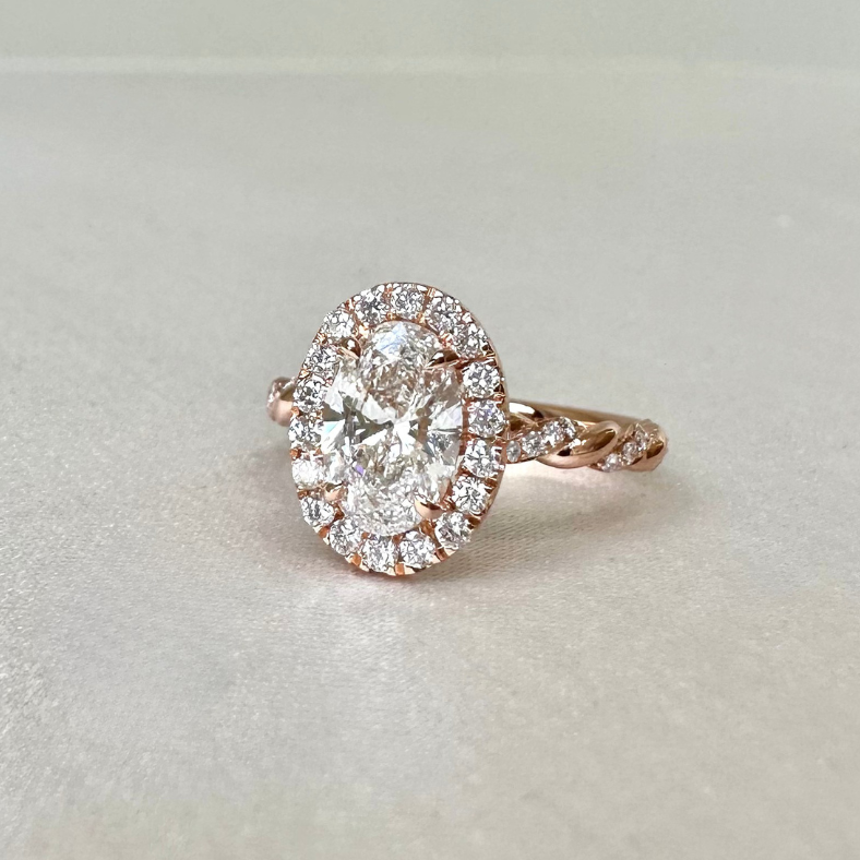 玫瑰金橢圓形鑽石求婚戒，搭配華麗的halo圍鑽與扭臂戒身設計，呈現浪漫復古的訂婚鑽戒風格。